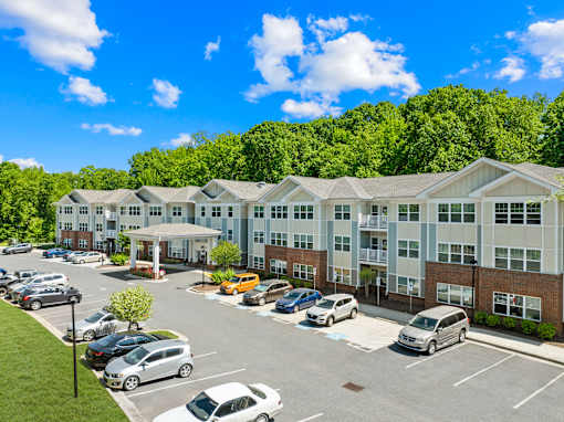 A parking lot in front of a large building with cars parked.