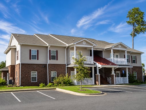 A large two-story apartment building with a parking lot in front.