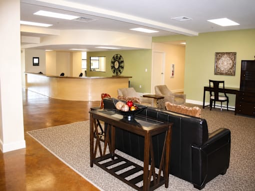 A living room with a black leather couch and a wooden coffee table.