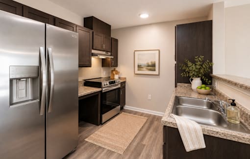 A modern kitchen with a stainless steel refrigerator and dark wood cabinets.