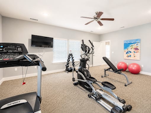 A home gym with a treadmill, exercise bike, and weights.