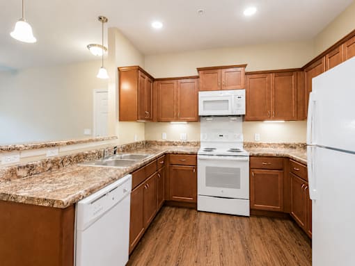 A kitchen with brown cabinets and white appliances.