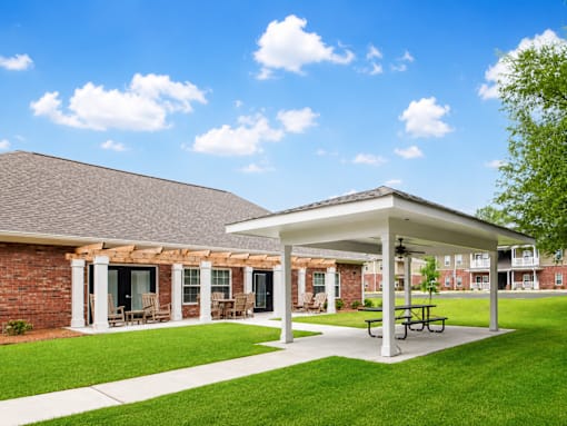 A covered patio area with a picnic table in front of a brick building.