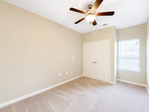 A room with a ceiling fan and a white door.