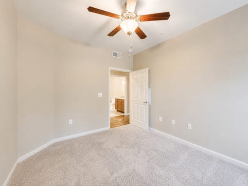 A room with a ceiling fan and carpeted floor.