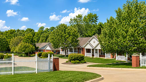 A white picket fence surrounds a brick house.