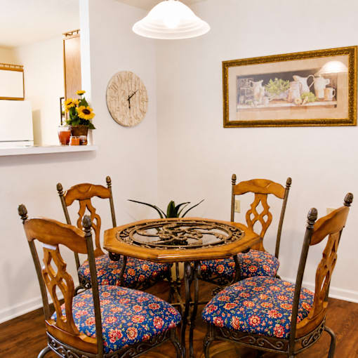 A table with four chairs and a clock on the wall.