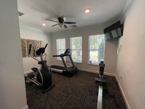 a home gym with exercise equipment and a ceiling fan