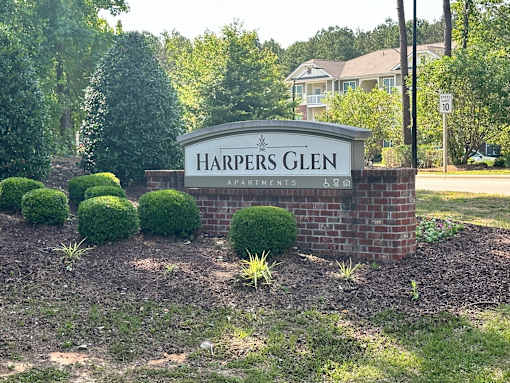 a sign for harpers glen in front of a garden