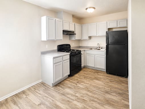 A kitchen with black appliances and white cabinets.