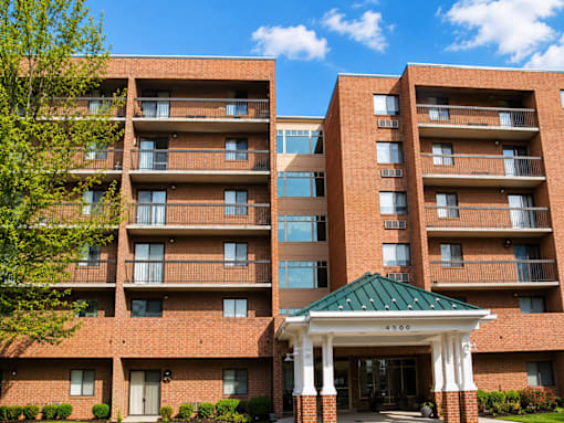 A large brick building with a green roof and a covered walkway entrance.