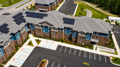 A parking lot in front of a building with solar panels on the roof.