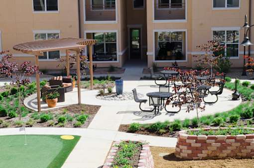 A patio with a table and chairs is surrounded by a garden.