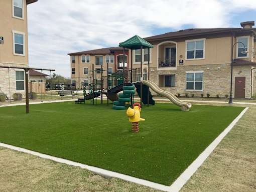 A playground with a yellow duck slide in front of a building.