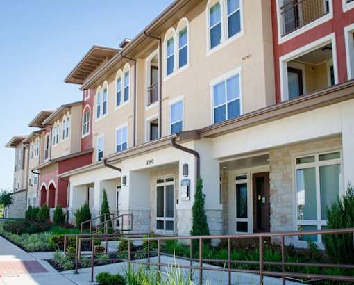 A row of apartment buildings with balconies and doors.