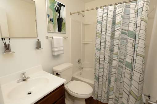 A bathroom with a white sink, toilet, and a shower curtain.