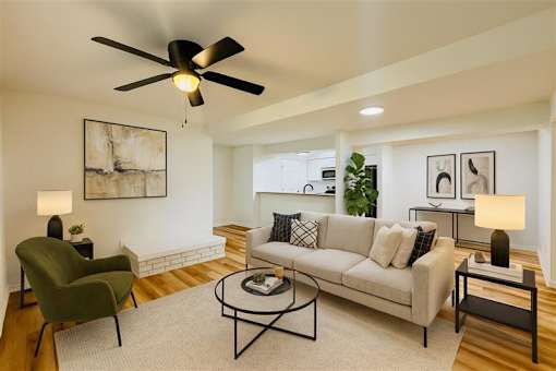A living room with a green chair, a white couch, and a ceiling fan.
