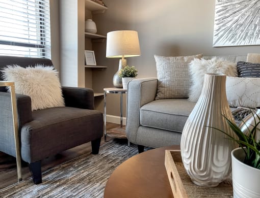 a living room with two chairs and a table and a vase