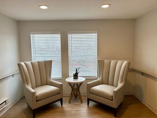 Two chairs and a table are in a room with white walls.