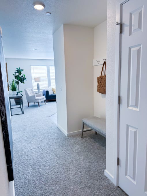 a hallway with a bench and a living room with couches and a table