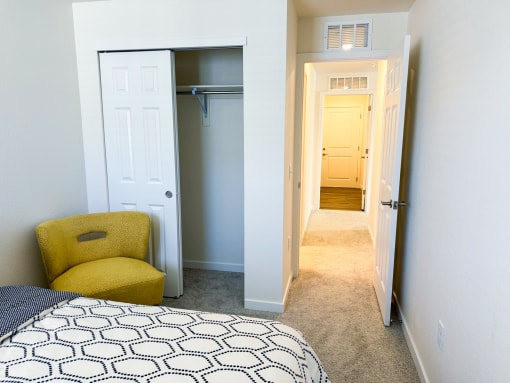 a bedroom with a closet and a bed and a yellow arm chair