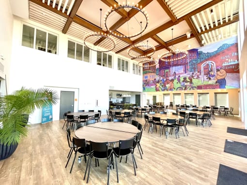a large dining room with tables and chairs and a mural on the wall