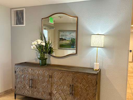 A wooden cabinet with a vase of flowers on top and a mirror above it.