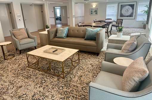 A living room with a patterned carpet and furniture including a sofa, armchairs, and a coffee table.