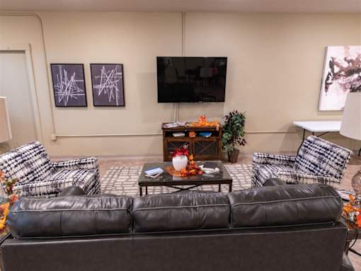 A living room with a black leather couch and a coffee table with a vase of flowers on it.