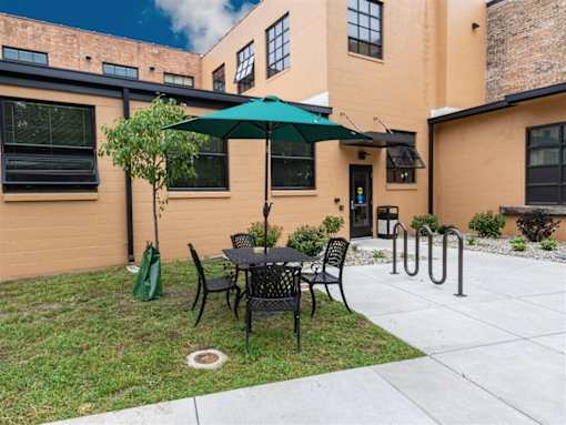 A patio with a table and chairs and a green umbrella.