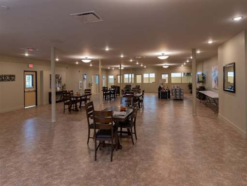 A large room with tables and chairs is well lit with natural light.