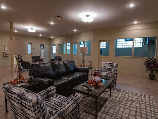 A living room with a black couch, a coffee table, and a chair.
