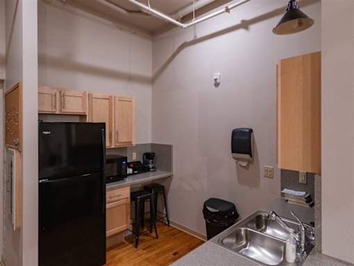 A kitchen with a black fridge and wooden cabinets.