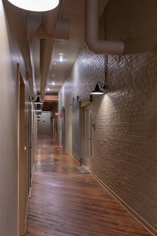 A long hallway with a brick wall and wooden floors.