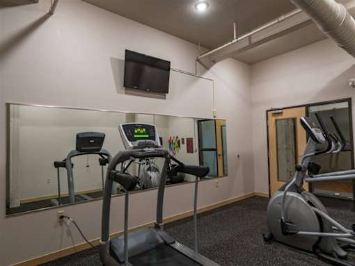 A gym with treadmills, a stationary bike, and a television mounted on the wall.