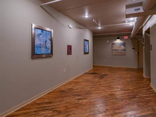 A hallway with wood floors and artwork on the walls.