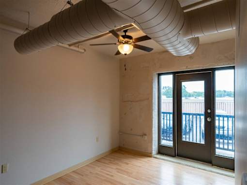 A room with a ceiling fan and a door leading outside.