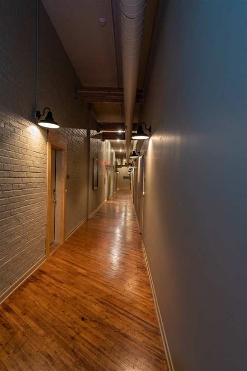 A long hallway with wooden floors and brick walls.