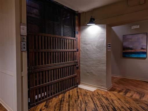 A room with a wooden floor and a white wall with a painting hanging on it.