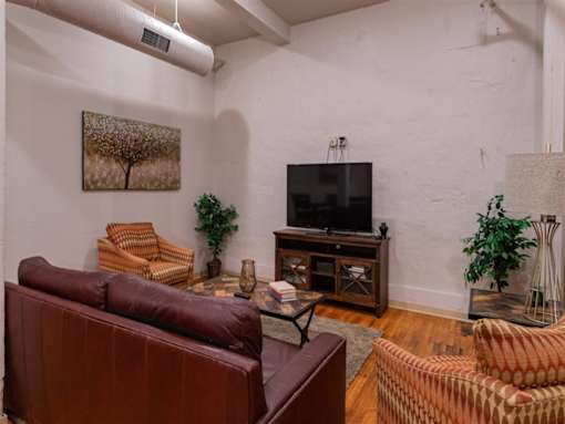 A living room with a brown leather couch and a television.