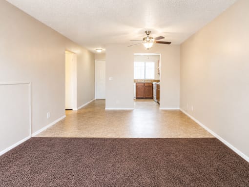 A room with a brown carpet and a ceiling fan.