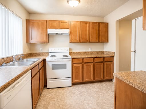 A kitchen with a white stove and wooden cabinets.