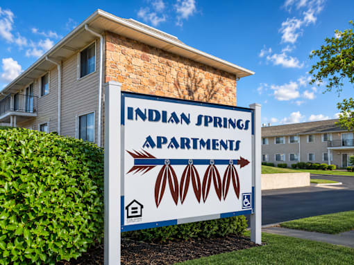 A sign for Indian Springs Apartments stands in front of a building.