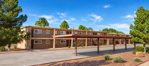 A building with a brown facade and a parking lot in front.