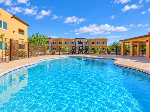 A swimming pool in front of a building with a fence around it.