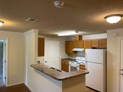 A kitchen with white appliances and wooden cabinets.