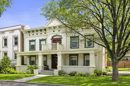 A white two-story house with a red door and a balcony.