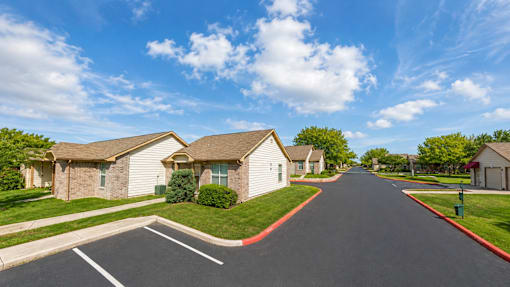A street view of a residential area with houses on both sides and a clear blue sky.