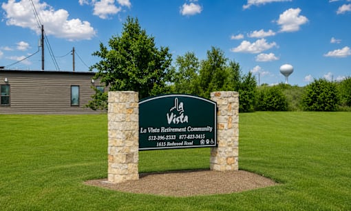 A sign for La Vista Retirement Community stands in a grassy field.