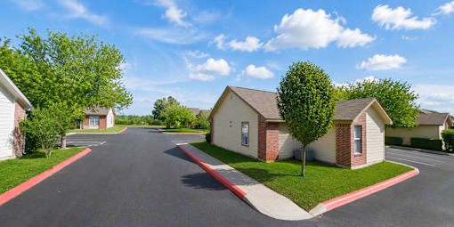 A residential street with houses on both sides and a tree in the middle.